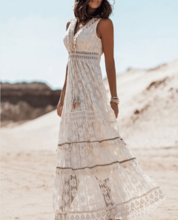 White crochet boho maxi dress for women, featuring intricate lace-like texture and playful fringe hem. Summer style.