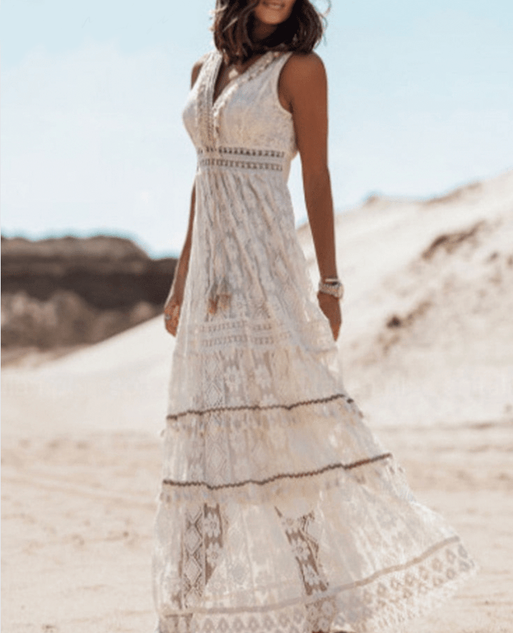 White crochet boho maxi dress for women, featuring intricate lace-like texture and playful fringe hem. Summer style.