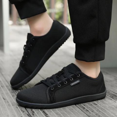Side view of black unisex zero-drop walking shoes, showcasing lace-up design and slip-resistant outsole.