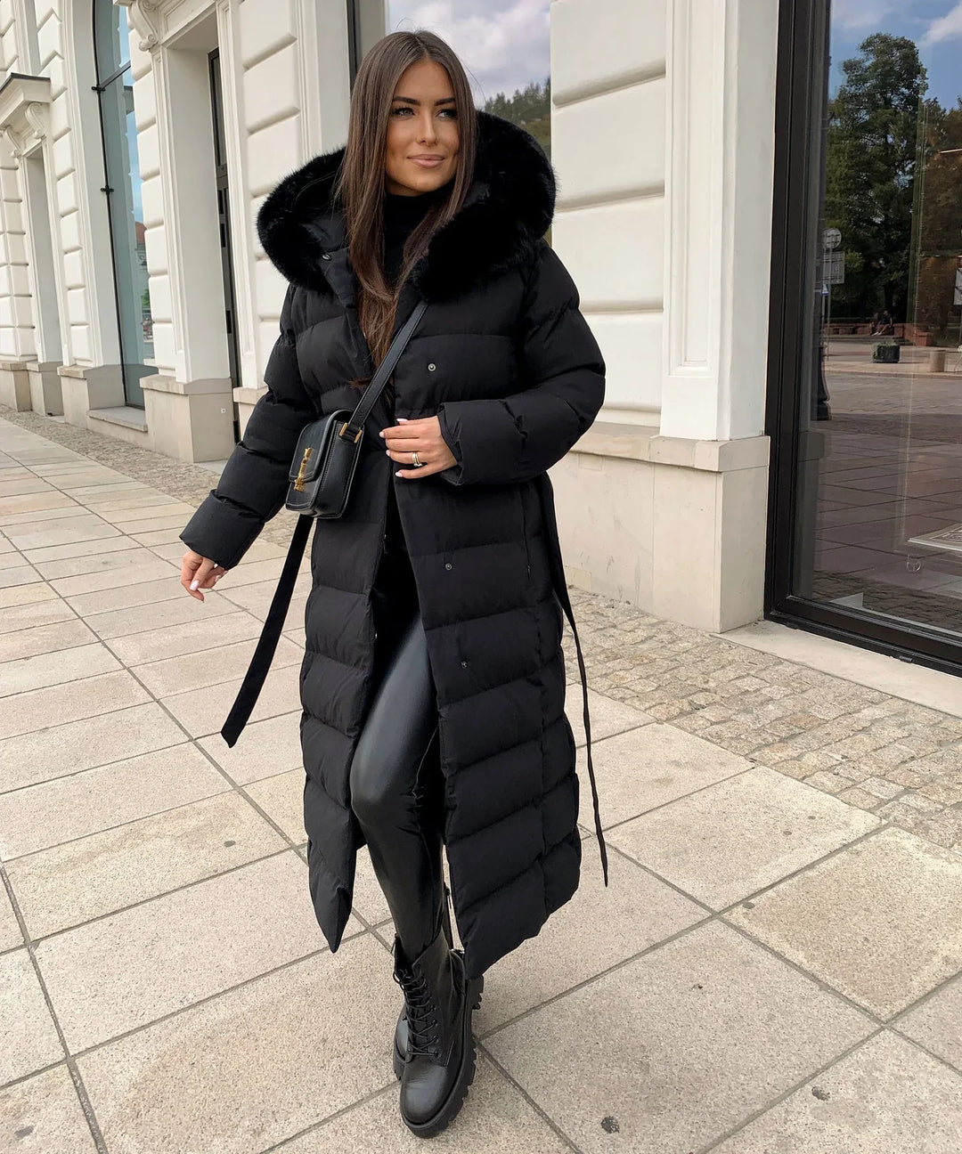 Stylish woman wearing a black belted puffer winter coat, ready for cold weather outerwear.