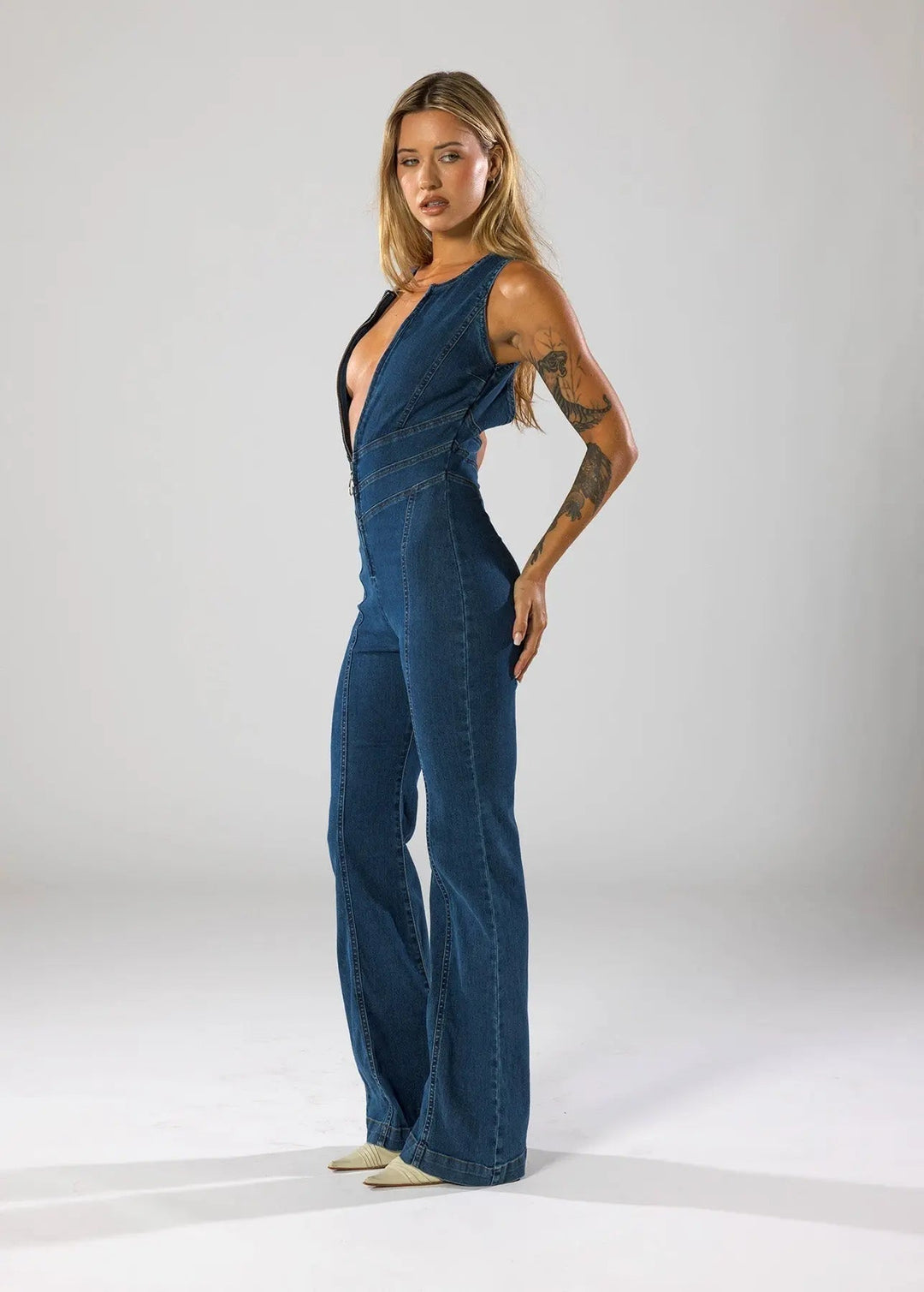Women's blue fitted flared jumpsuit with a daring plunge neck. Sleeveless design, great for evening parties.