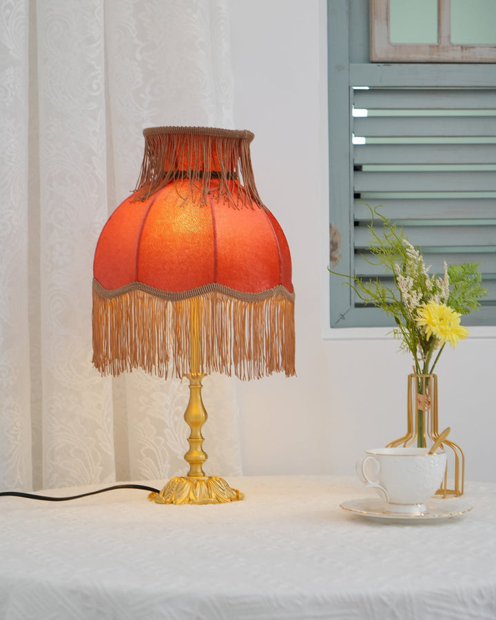 Red table lamp for bohemian decor, stylish tassel accent provides warm ambient lighting.