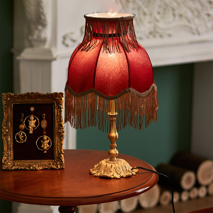Unique red bohemian table lamp with decorative tassels, providing a warm glow for bedrooms.
