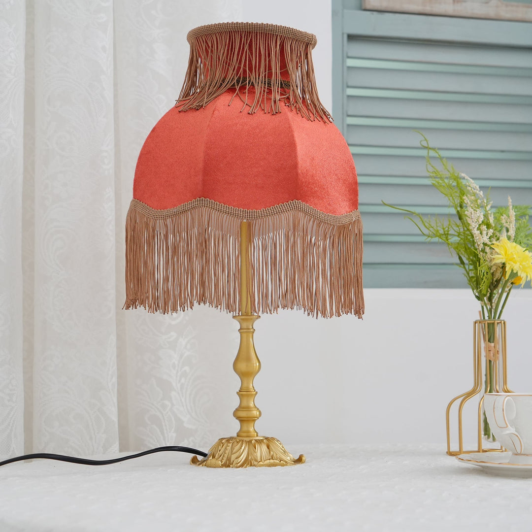 Decorative red table lamp with bohemian flair and warm lighting, a tassel masterpiece.