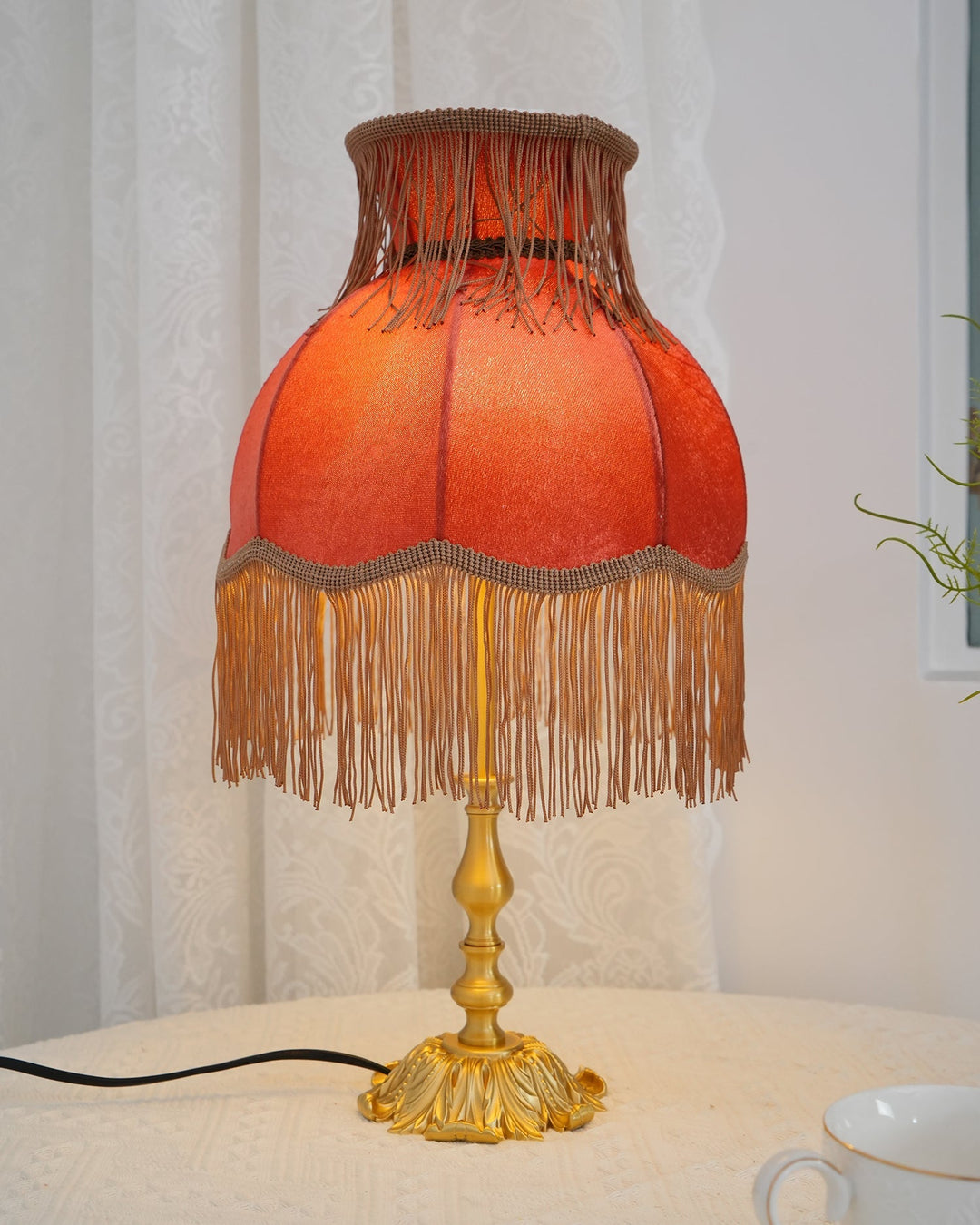 Living room accent: red bohemian table lamp featuring elegant tassels & warm light, unique.