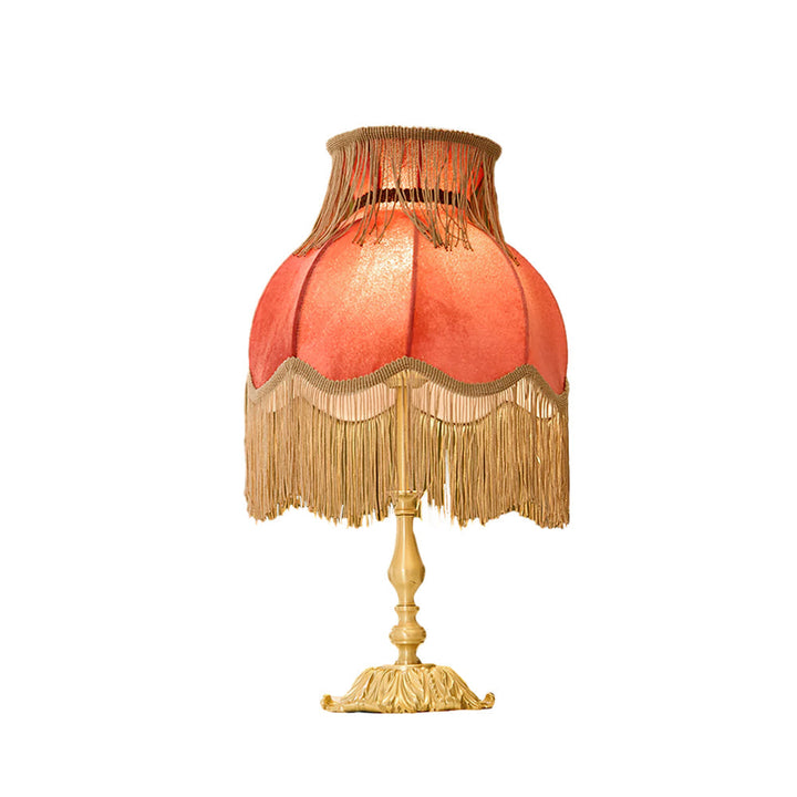 Red bohemian table lamp, charming tassel detail provides soft, warm-toned lighting.