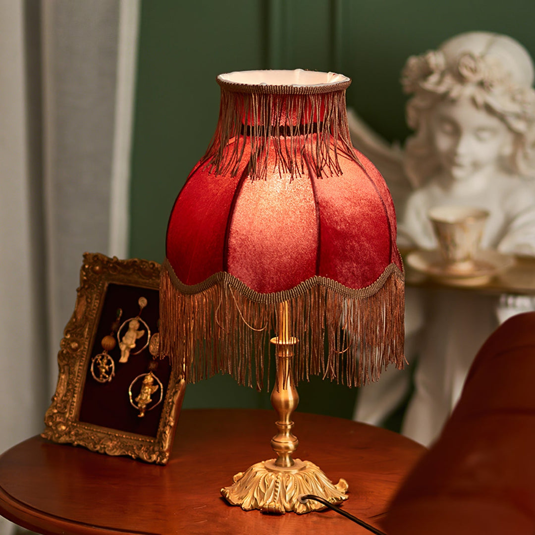 Warm-toned red table lamp, bohemian style with elegant tassels, perfect for home accent lighting.