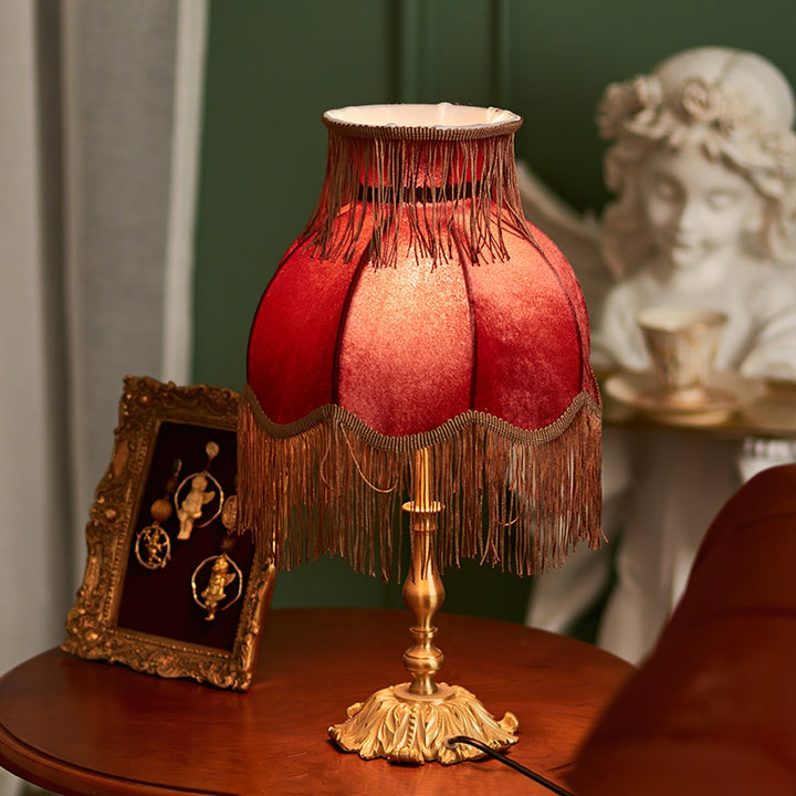 Warm-toned red table lamp, bohemian style with elegant tassels, perfect for home accent lighting.
