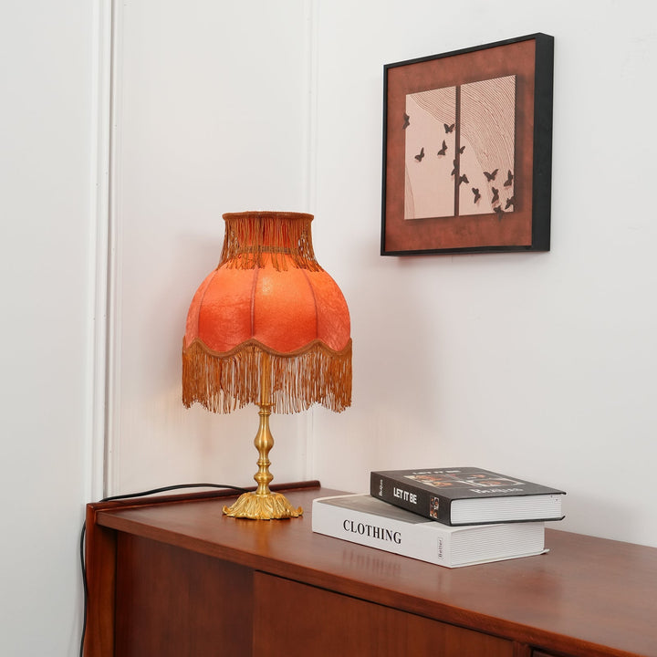 Bedroom accent lamp, red bohemian design with soft warm glow & decorative tassels.