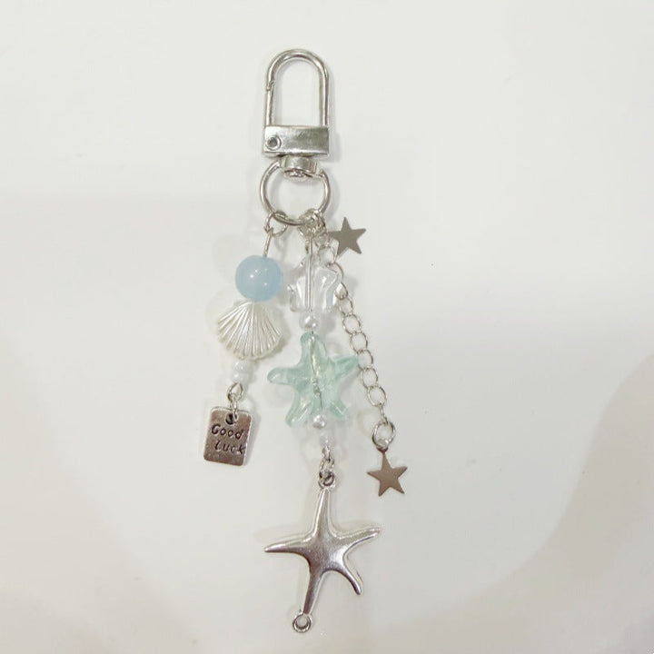 Detailed metal maritime keychain showcasing a starfish, shell, and rope design. Unisex accessory.