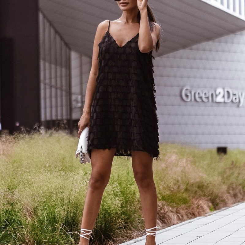 Descriptive view of a women's V-neck sleeveless mini dress, highlighting the textured tassel and fringe for chic style.