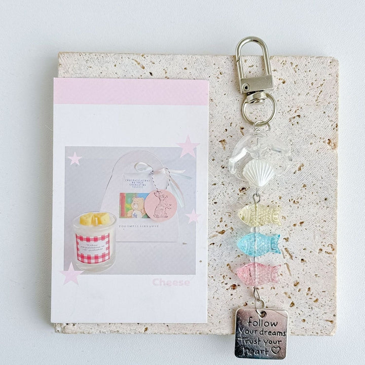Detailed plastic nautical charm keychain displaying vibrant marine fish and shell designs. Great ocean accessory.