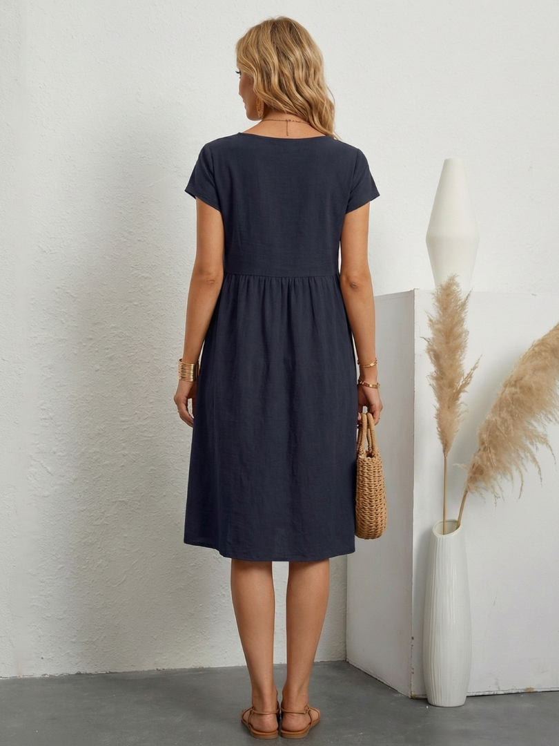 Solid color relaxed fit women's short sleeve knee-length dress with pockets, great for casual elegance.