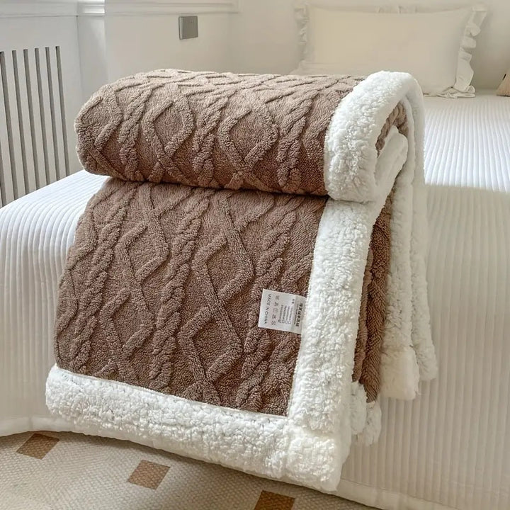 Soft Sherpa fleece blanket spread on a bed, providing cozy comfort & warmth for a relaxing bedroom atmosphere.
