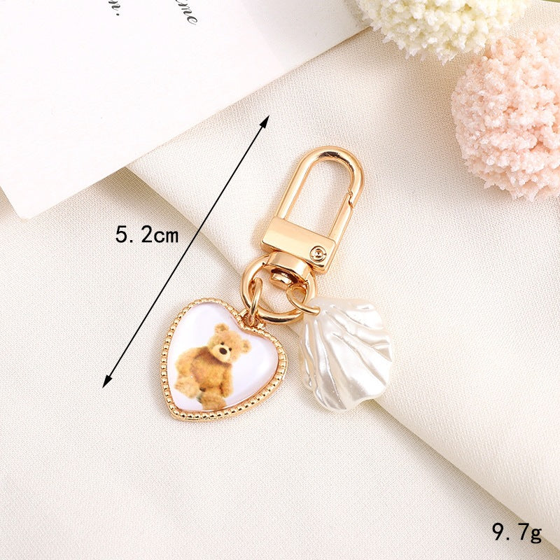 Heart-shaped bear keychain with a metallic bell, a fun and cute accessory for backpacks.