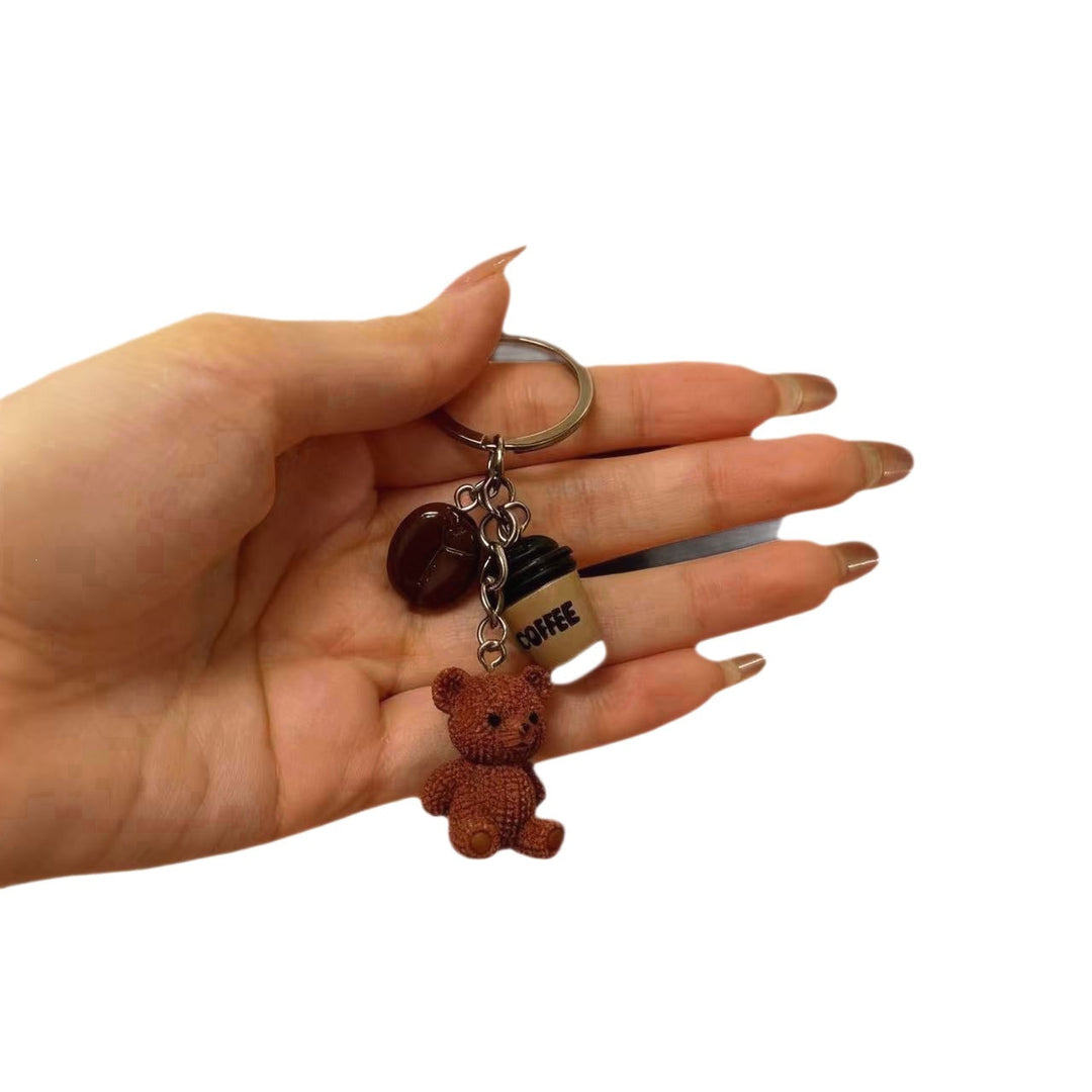 Sweet bear holding a drink cup keychain. Cute animal charm for bags or keys. Playful, unique accessory.