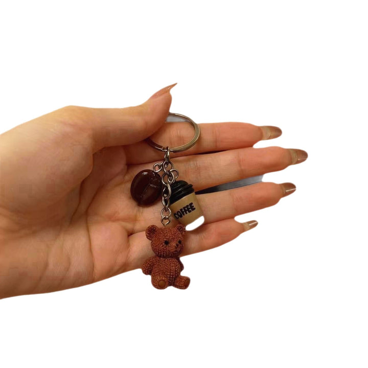 Sweet bear holding a drink cup keychain. Cute animal charm for bags or keys. Playful, unique accessory.