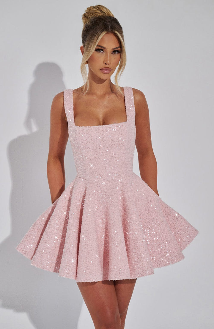 Woman models dazzling pink sequin bow mini dress. Ideal women's party dress, perfect for evening wear events.