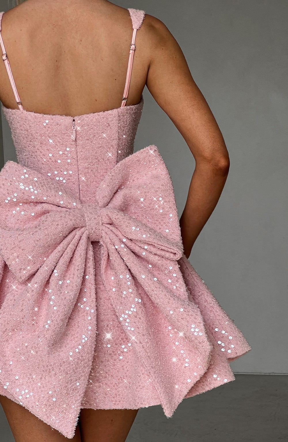 Close-up of sparkling sequin texture on a sleeveless bow mini dress. Dazzling women's party & cocktail wear.