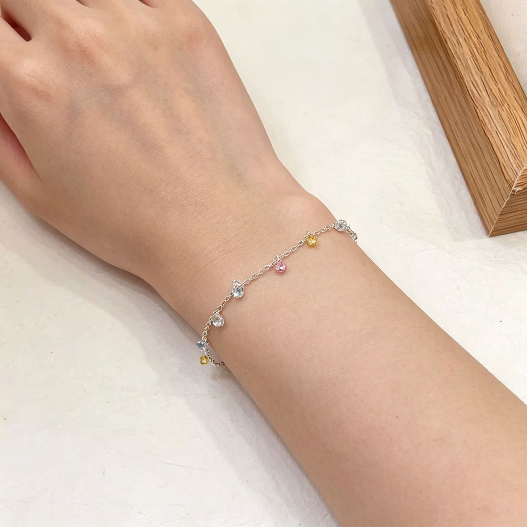 Close-up of a dazzling silver charm ankle bracelet, showcasing elegant women's jewelry details.
