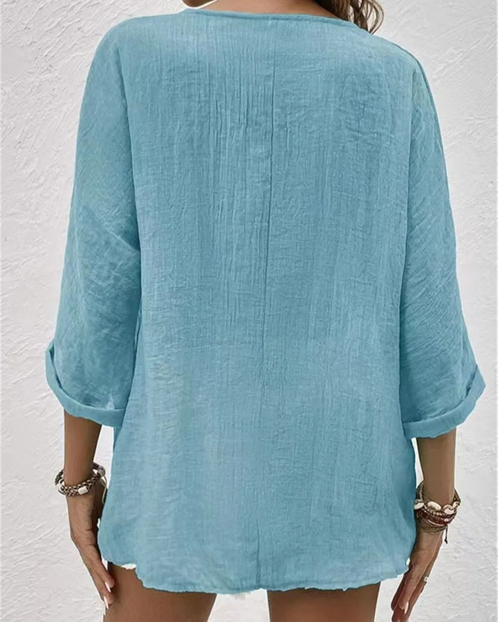 Fashionable women's blouse with a deep v-neck, button-front, and rolled sleeves, suitable for any occasion.