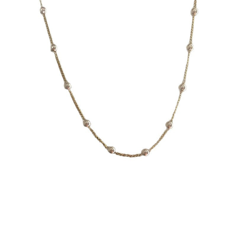Minimalist women's gold necklace with a luminous white pearl. A delicate and elegant fashion accessory.