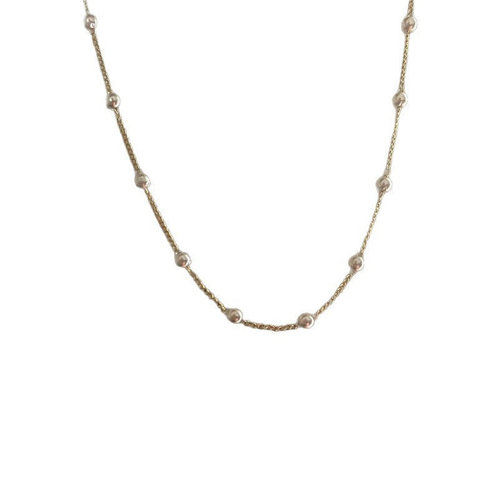 Minimalist women's gold necklace with a luminous white pearl. A delicate and elegant fashion accessory.