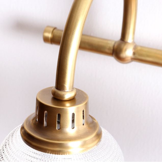 Close-up of elegant antique brass wall sconce showcasing textured glass and detailed finish.