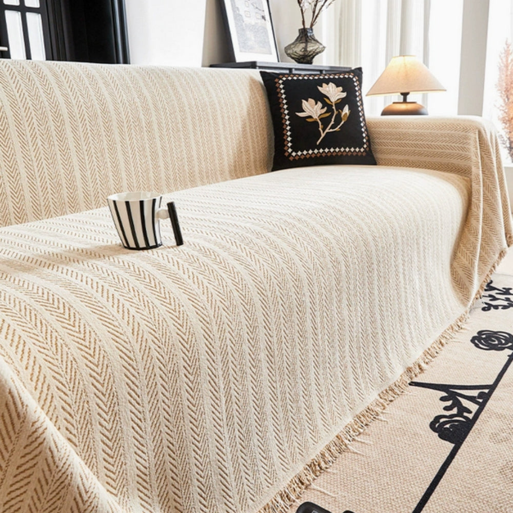 Elegant beige herringbone chenille sofa cover with tassels. Soft, durable furniture protector for living room decor.