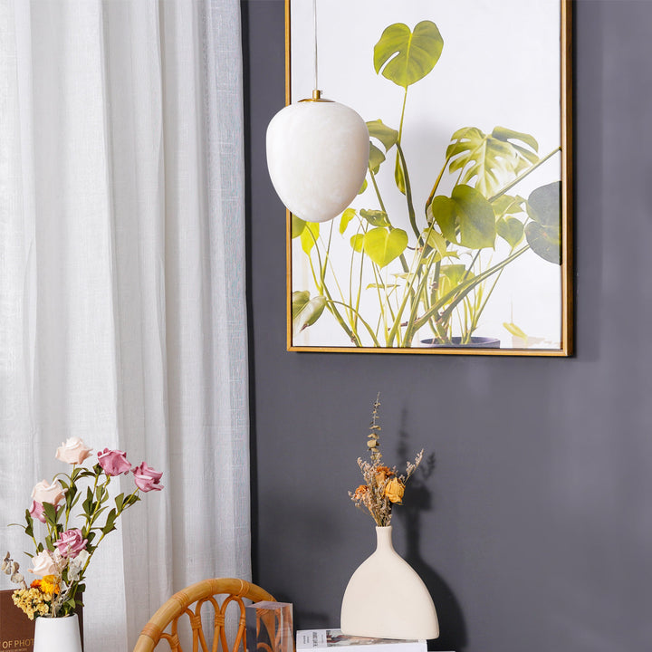Elegant brass pebble pendant for modern interiors, offers gentle ambient lighting.