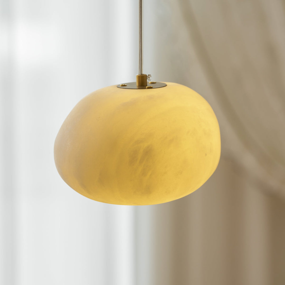 Brass pebble pendant light, minimalist and elegant, perfect for serene home interiors.