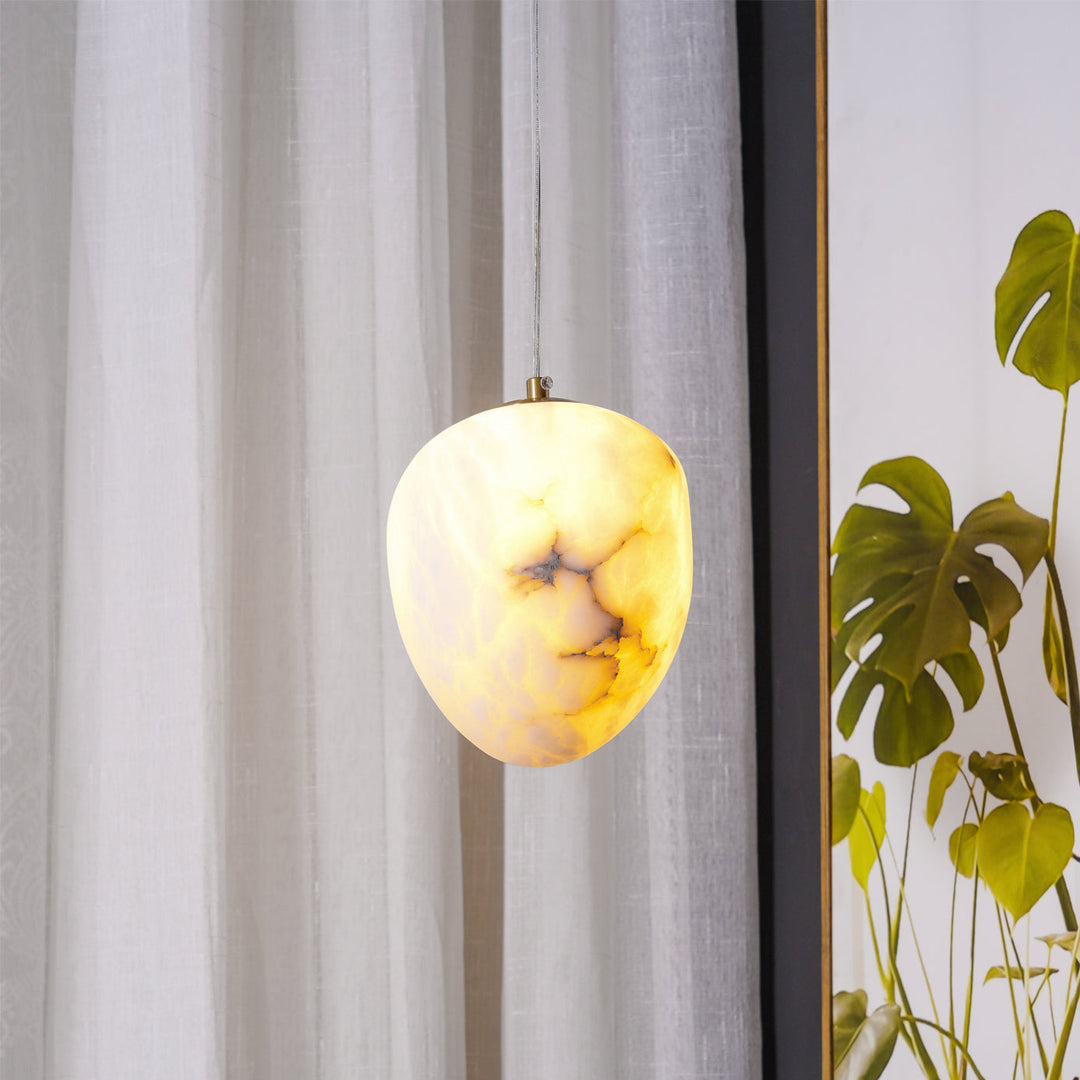 Brass pebble pendant fixture, elegant and modern, enhances home ambient lighting.