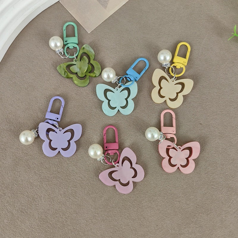 Elegant butterfly & pearl keychain charm for women, a stylish accessory for keys or bags.