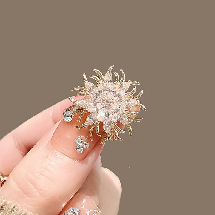 Golden metal sun motif brooch with sparkling crystals, elegant women's lapel pin.
