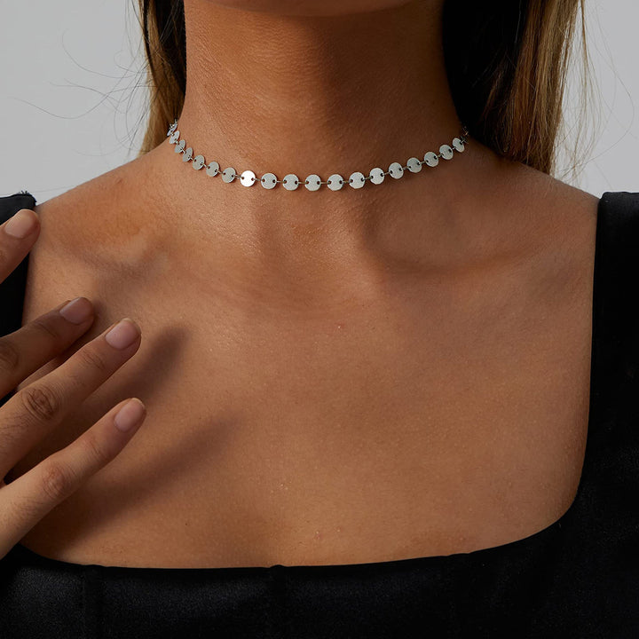 Stylish woman modeling a delicate gold choker necklace, showcasing its elegant and dainty appeal.