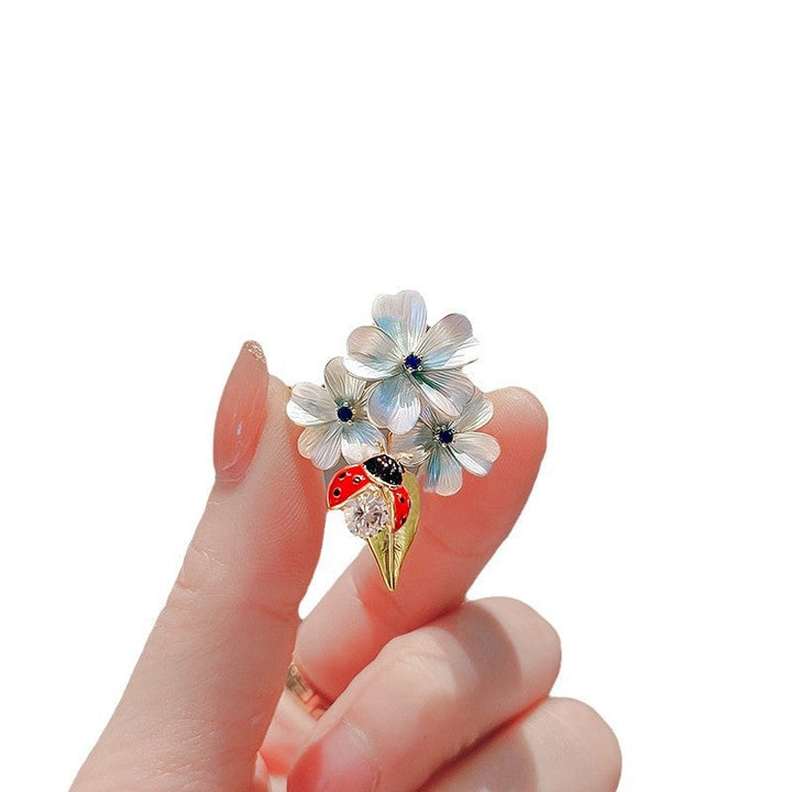 Statement piece: Elegant enamel flower ladybug brooch, showcasing intricate design and crystal brilliance.