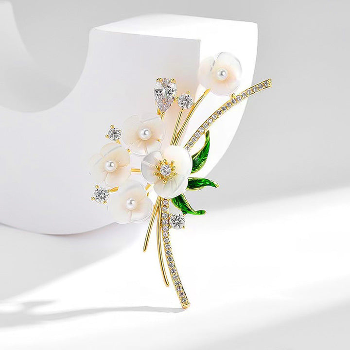 Women's floral rhinestone & pearl brooch elegantly pinned on a classic garment, a stylish accessory.
