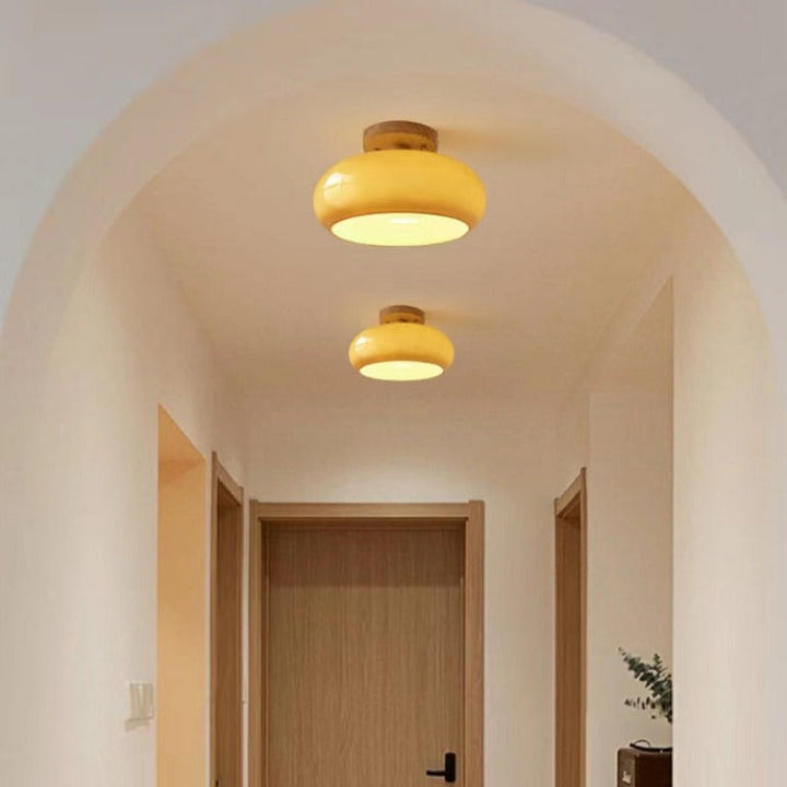 Modern flush mount ceiling light with a round wood base & sleek glass diffuser, perfect for living or dining rooms.