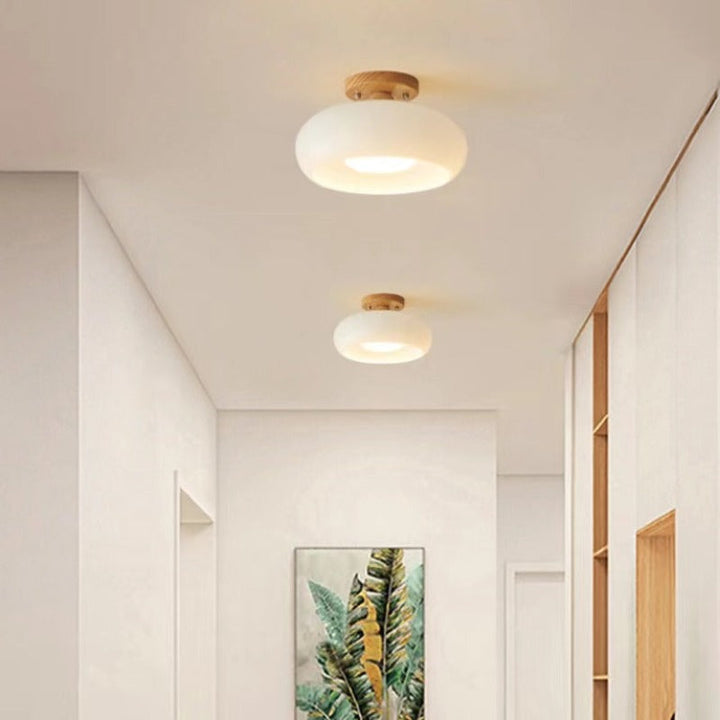 Natural style flush mount ceiling lamp. Features a warm wooden finish & opaque glass shade, enhancing any space.
