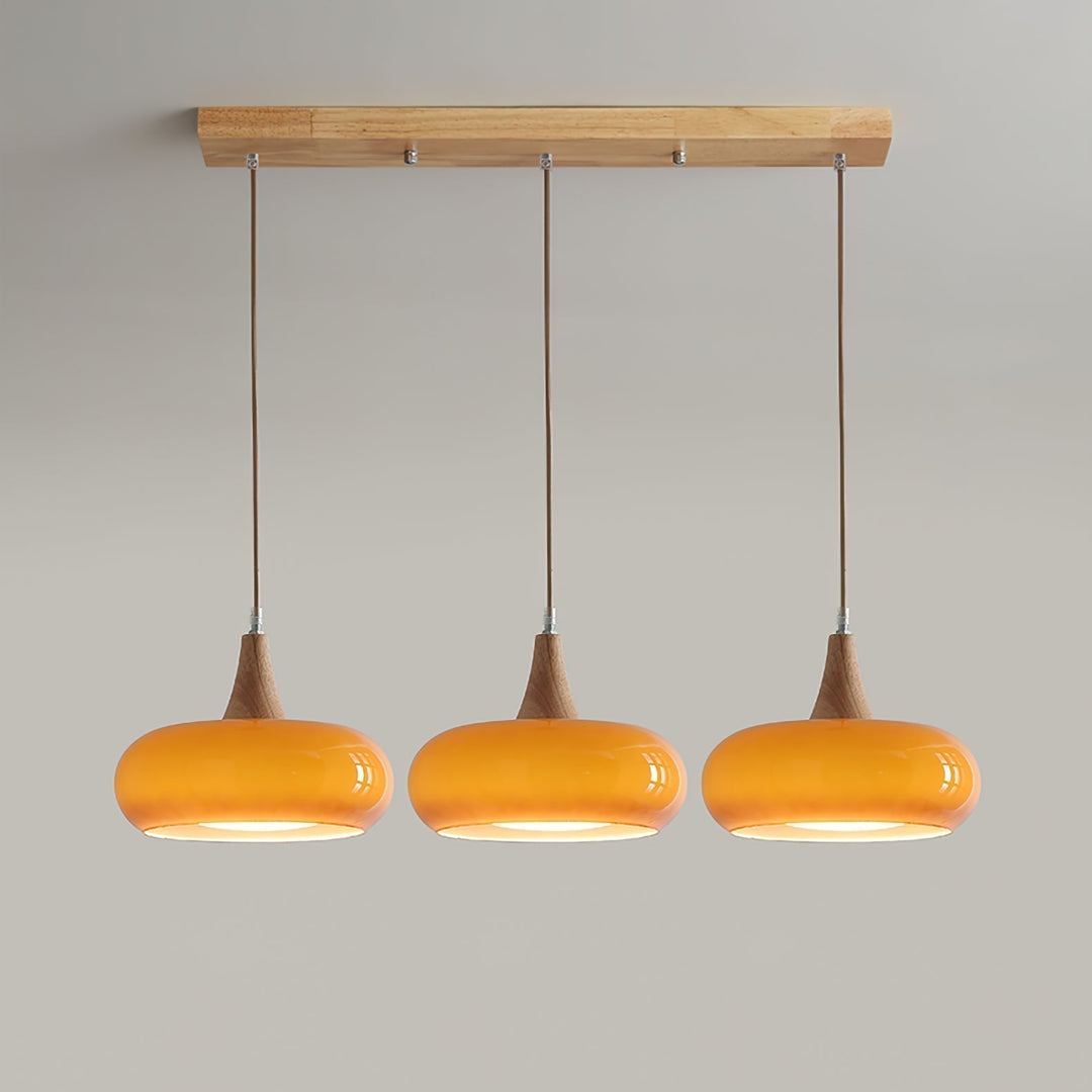 Contemporary glass & wood pendant light with black metal details. Modern kitchen lighting.