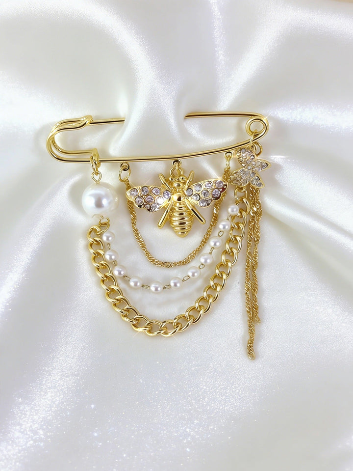 Fashionable gold safety pin brooch with an intricate crystal & pearl bee design. An elegant jewelry piece.