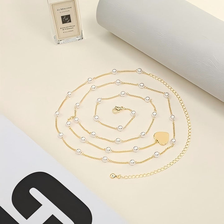 Adjustable women's gold waist chain with pearl & heart charms. Fashionable body jewelry, elegant accessory.