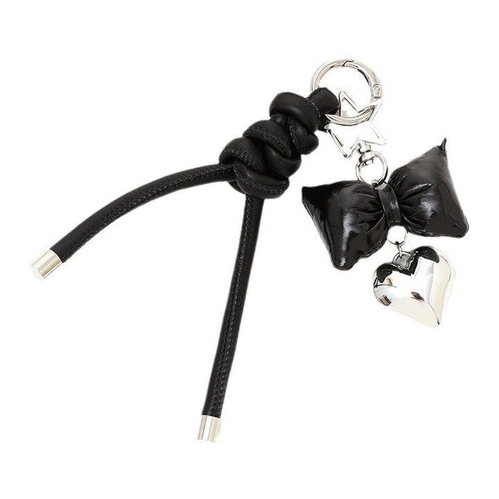 Women's elegant bow & heart keychain attached to a stylish leather bag.