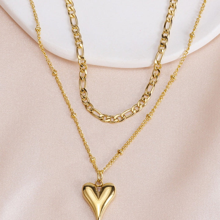 Chic double-layer gold necklace with two polished heart pendants. Modern women's fashion jewelry.