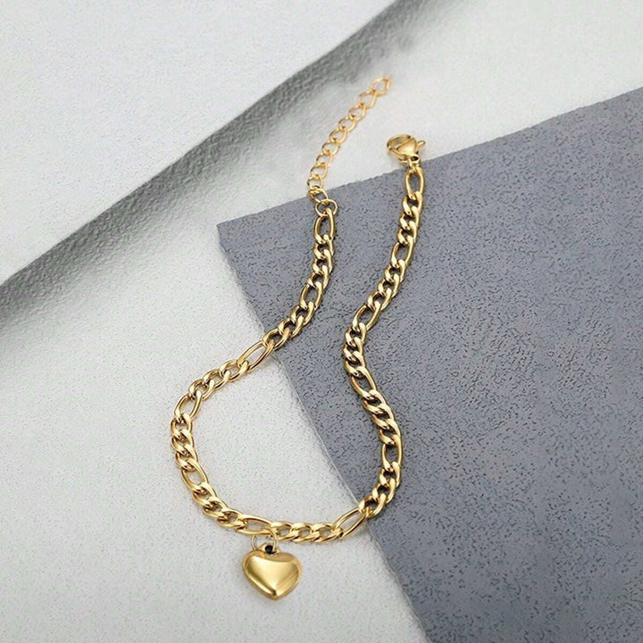 Close-up of a sophisticated white enamel heart charm on a gold-plated link bracelet for women.