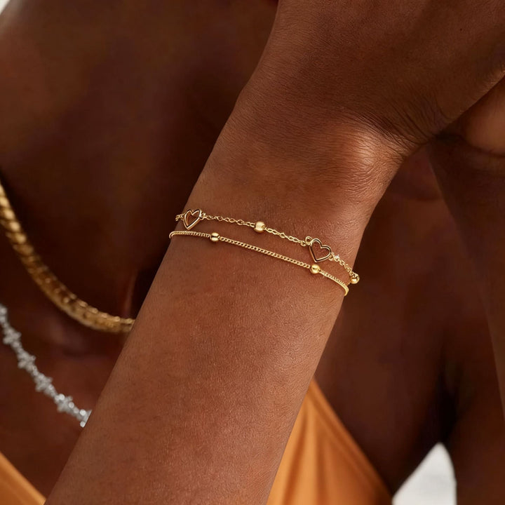 Women's elegant gold tone layered heart charm bracelet, a fashionable and adjustable jewelry accessory.