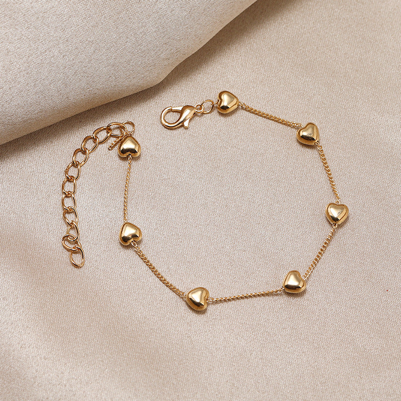 Elegant gold-tone women's bracelet with a delicate heart charm. Adjustable jewelry perfect for any occasion.