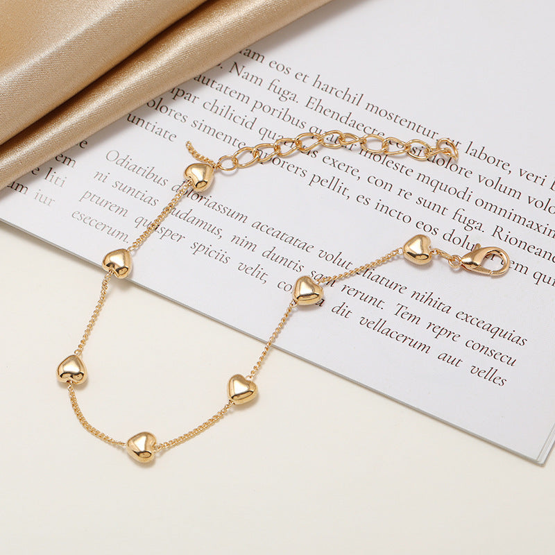 Close-up of an elegant gold-tone heart charm bracelet. Women's adjustable jewelry with a romantic appeal.