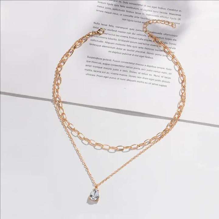 Close-up of the intricate design of a women's elegant gold layered chain with white details.