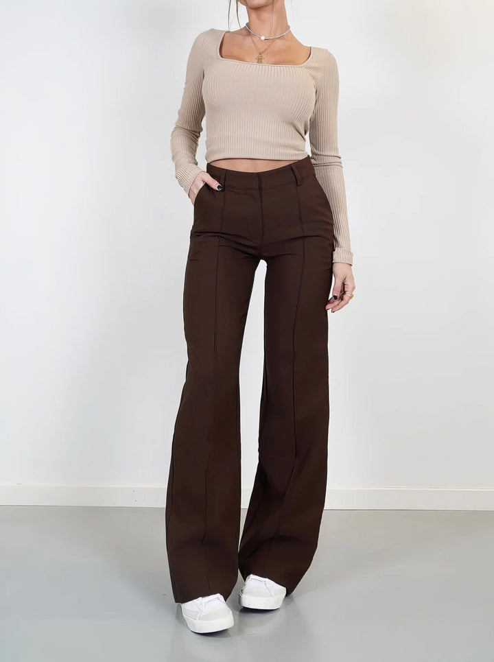 Front view: Woman in comfortable high-waisted wide-leg trousers, showcasing elegant fit.